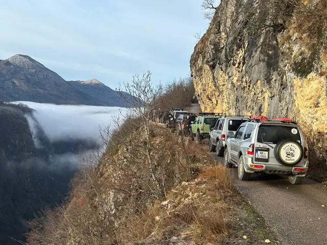 Kolona terenaca na uskom putu uz stijenu iznad magle