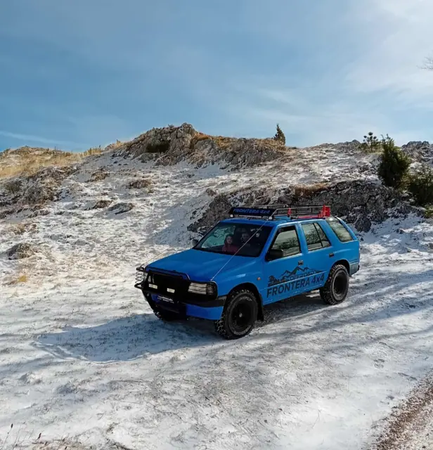 Plavi terenac na snježnoj kamenitoj padini