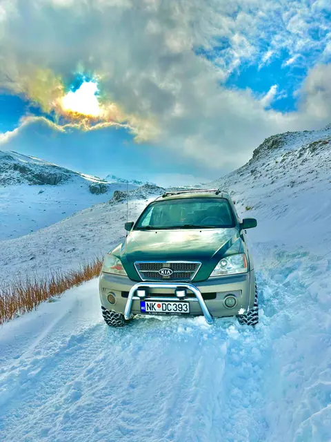 Terenac na snježnom putu ispod planinskih vrhova
