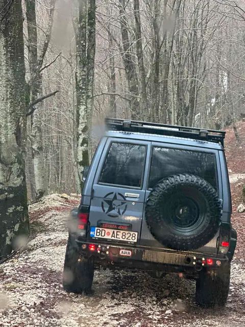 Terensko vozilo na uskom putu kroz listopadnu šumu