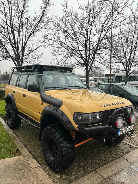 Žuti terenac sa krovnom opremom ispred kuće